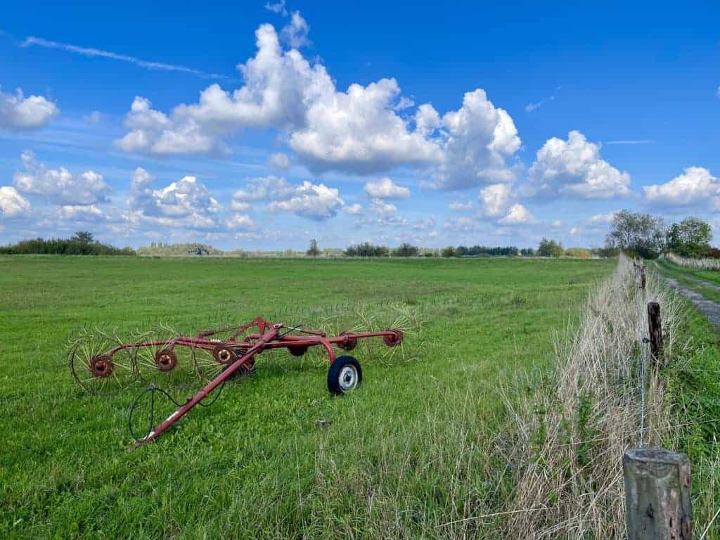 Gelders Eiland landschap met landbouwmachine onder een heldere blauwe hemel.