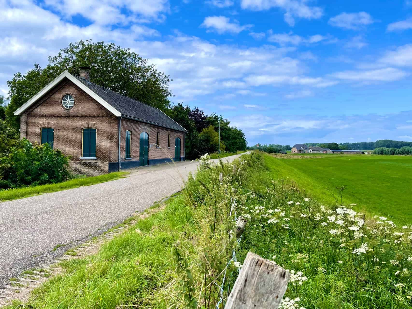 Traditionele boerderij op 't Gelders Eiland met groene velden en heldere lucht.