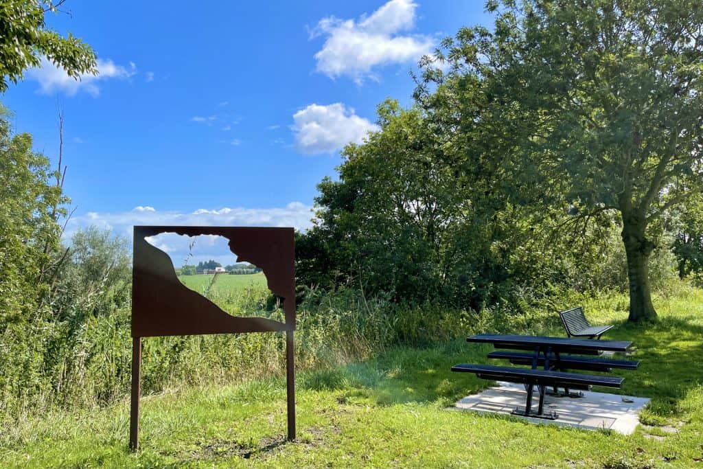Uitzicht op Gelders Eiland met bankjes en kunstwerk in de natuur.