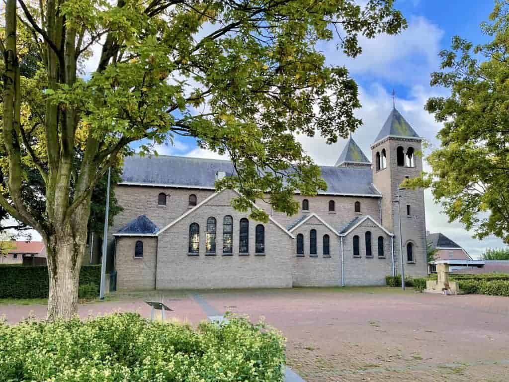Kerk op 't Gelders Eiland met groene bomen en blauwe lucht op de achtergrond.