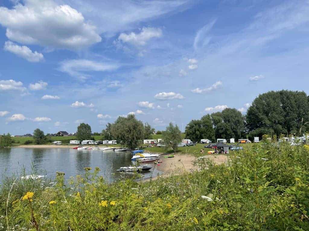 Gezicht op het strand en de camping op 't Gelders Eiland met boten en groene omgeving.