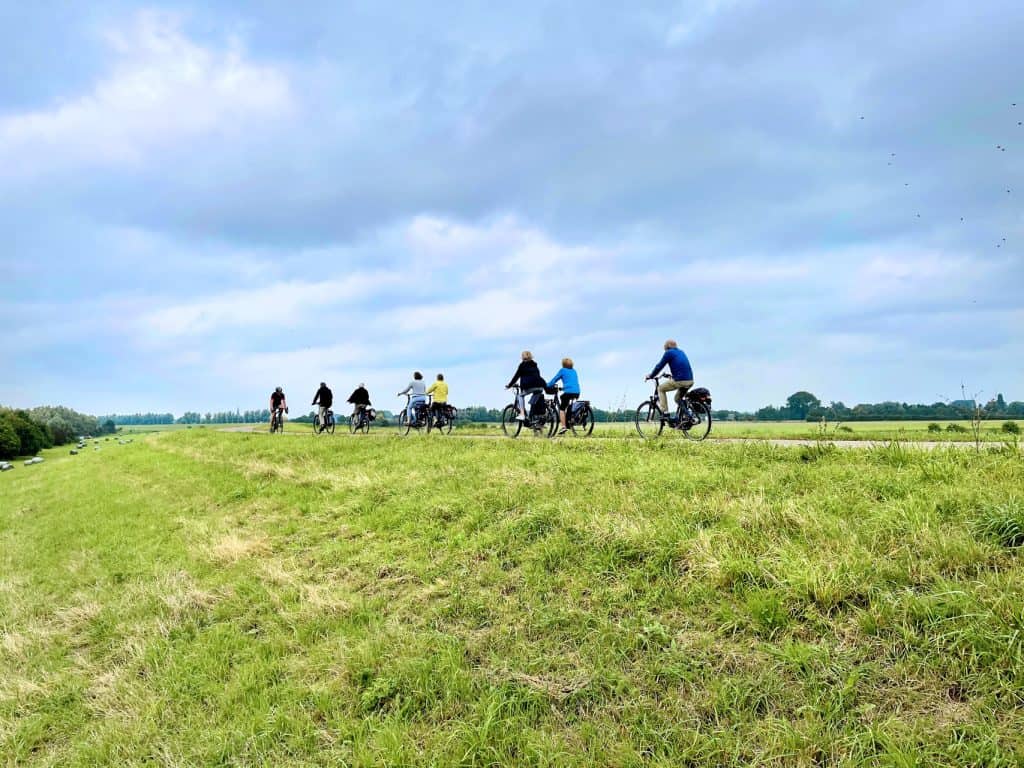 Groep fietsers op een grasveld met uitzicht op de natuur op 't Gelders Eiland.