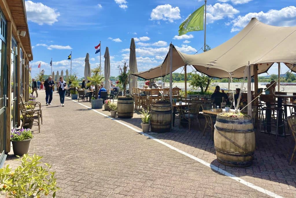 Gezellig terras met parasols en zitplaatsen op 't Gelders Eiland, ideaal voor genieten van het uitzi.