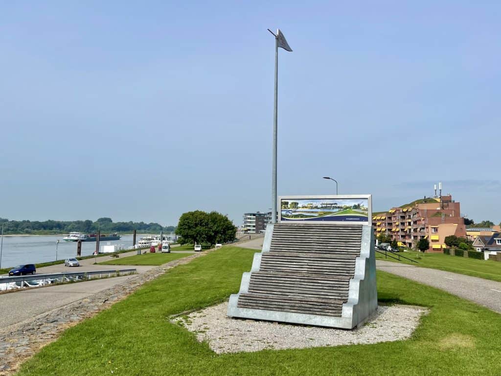 Promotiebeeld van 't Gelders Eiland met uitzicht op de rivier en wandelpromenade.