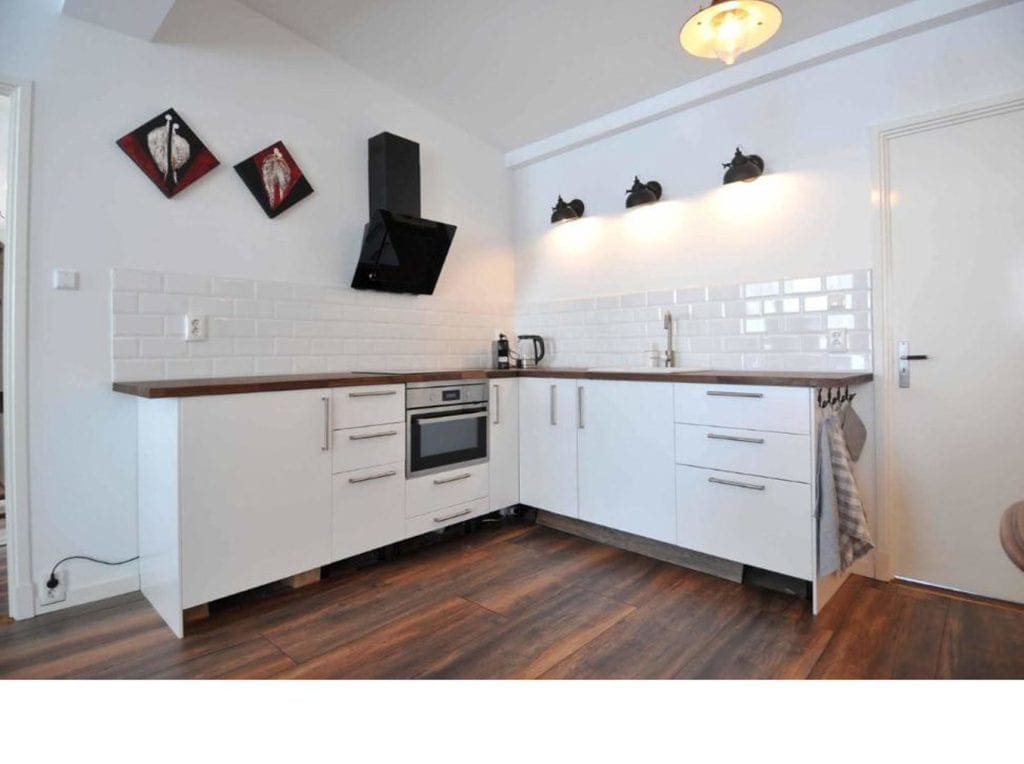 Moderne keuken in B&B De Tol met witte kasten en houten werkblad.