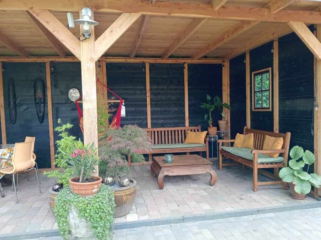 Gezellige veranda met houten meubels en groene planten op 't Gelders Eiland.