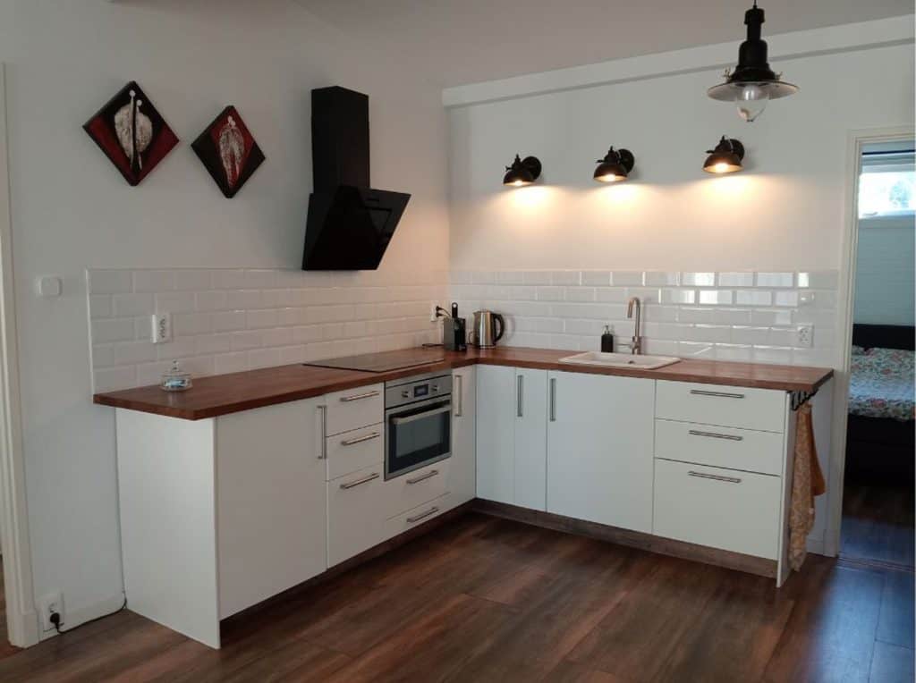Moderne witte keuken met houten werkblad en zwarte decoratie.