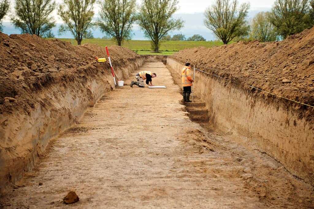 Archeologische opgraving op 't Gelders Eiland met onderzoekers in de grond.