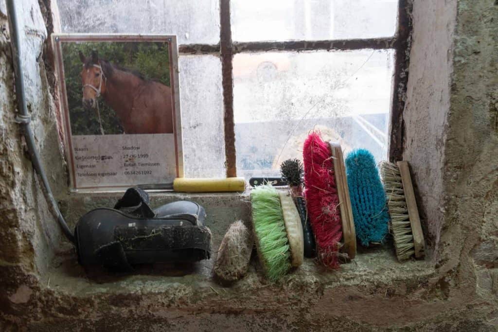 Paardensporen en verzorgingsproducten op een oud vensterbank in een stal.