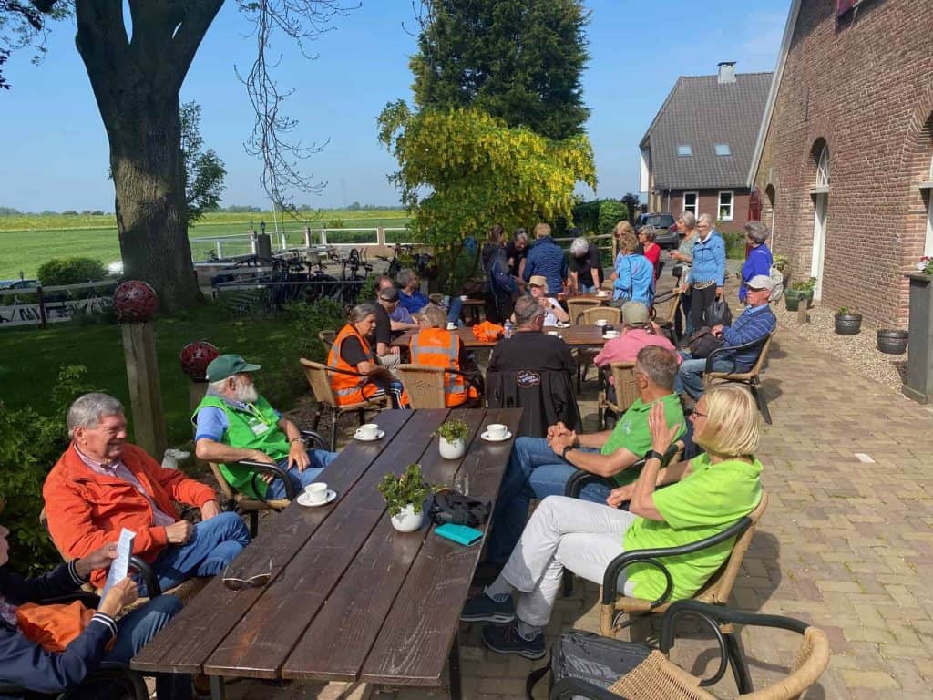 Gezellige groep mensen geniet van koffie en gesprekken op terras bij 't Gelders Eiland, met historis.