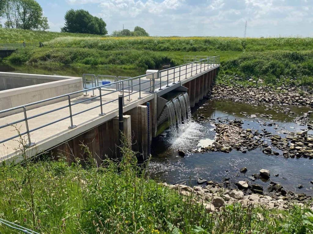 Kunstmatige waterafvoer op 't Gelders Eiland met groene omgeving en heldere hemel.
