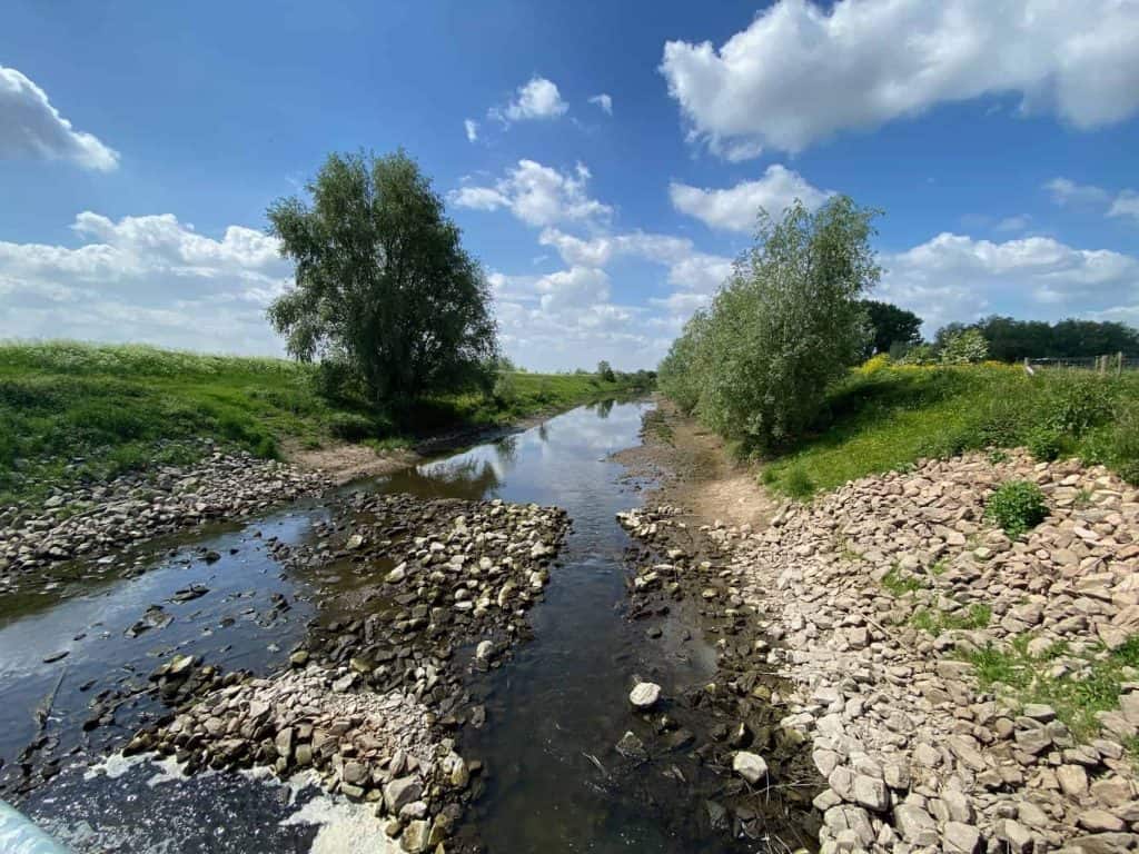 Natuurlijke rivier met groene oevers en blauwe lucht op 't Gelders Eiland.