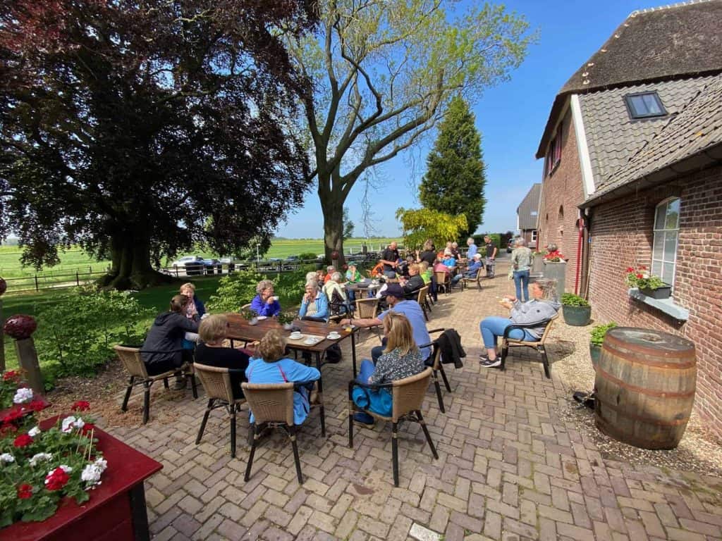 Gezellig terras op 't Gelders Eiland met mensen die genieten van het mooie weer.