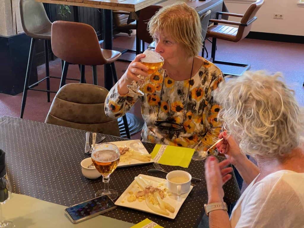 Een vrouw drinkt een glas bier in een gezellige café setting.