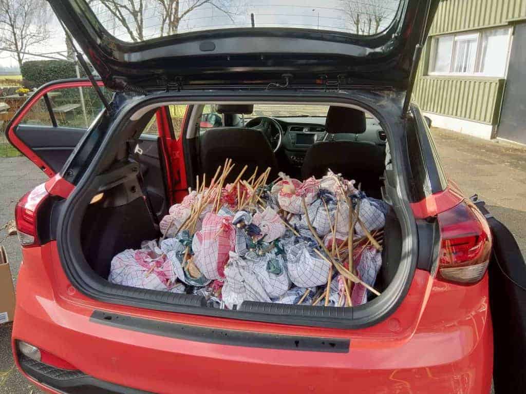 Zakken met afval in de achterbak van een rode auto op 't Gelders Eiland.