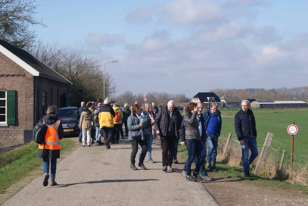 Gezelschap wandelt langs het platteland op 't Gelders Eiland, genietend van de landelijke omgeving e.