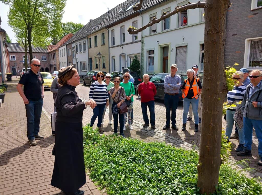 Gezelschap toeristen luisteren naar gids op 't Gelders Eiland, historische wijk met kleurrijke huize.