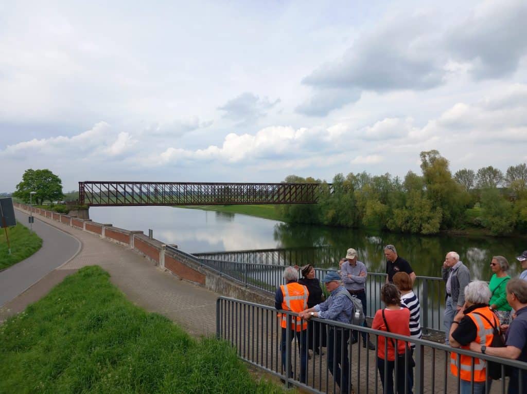 Groep wandelaars met veiligheidshesjes langs de rivier op ’t Gelders Eiland.