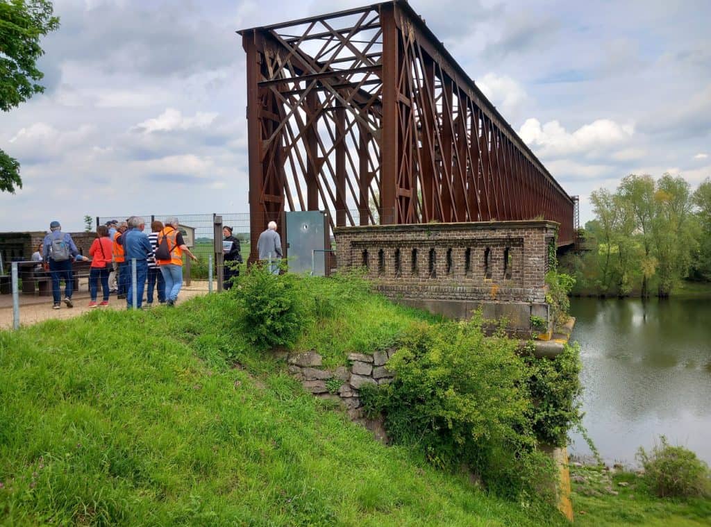 Hoge stalen brug over de rivier op 't Gelders Eiland met bezoekers en groene omgeving.