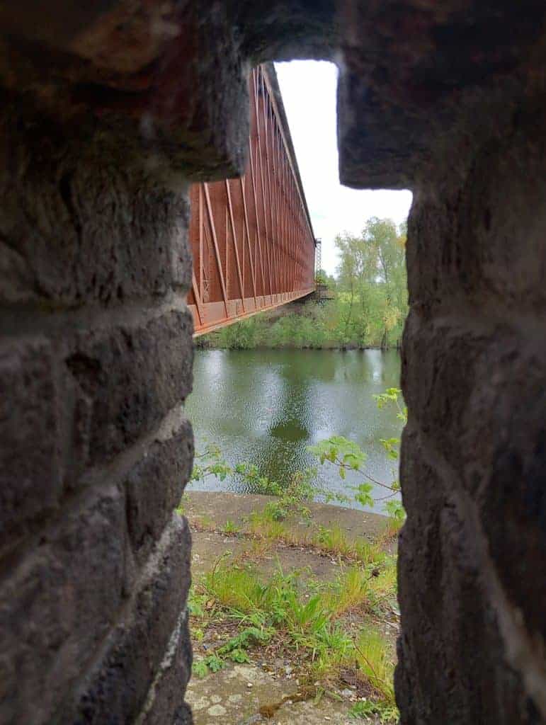 Brug tussen stenen met uitzicht op rivier en groene omgeving op 't Gelders Eiland.