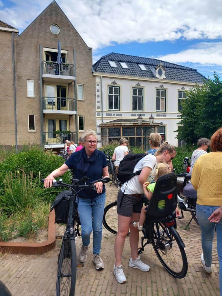 Fietsen en mensen in een gezellig buitengebied op 't Gelders Eiland, met historische gebouwen en gro.
