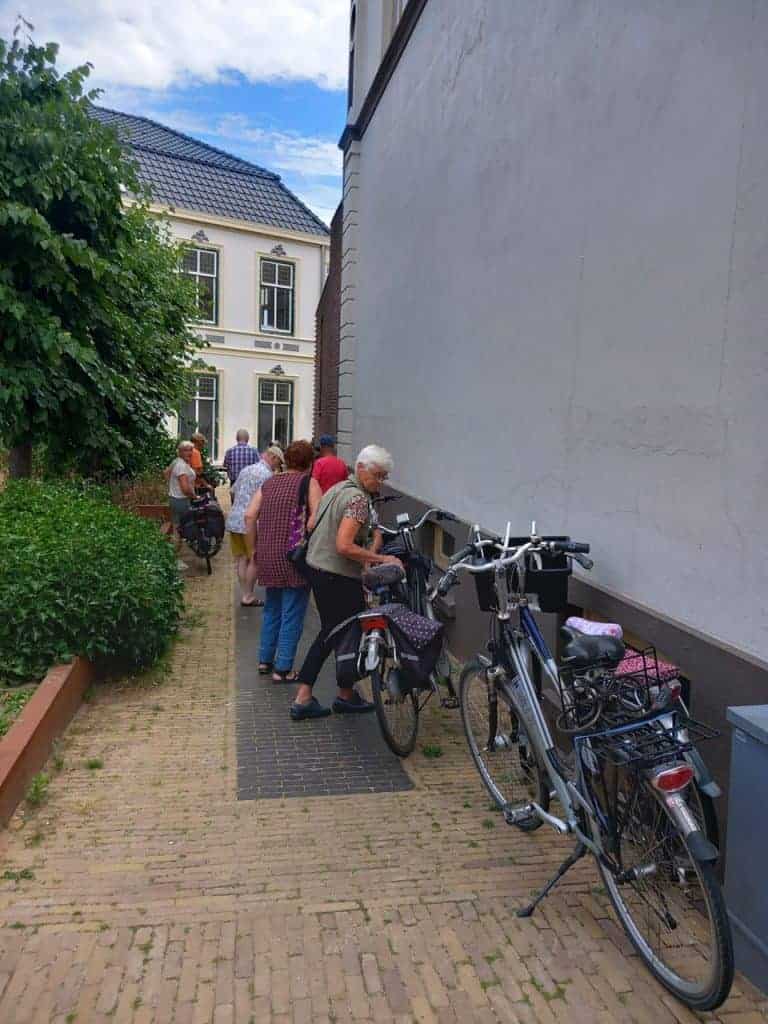 Gezellige buurtbewoners bij waterkraan op 't Gelders Eiland, fietsen en sociale interactie in histor.