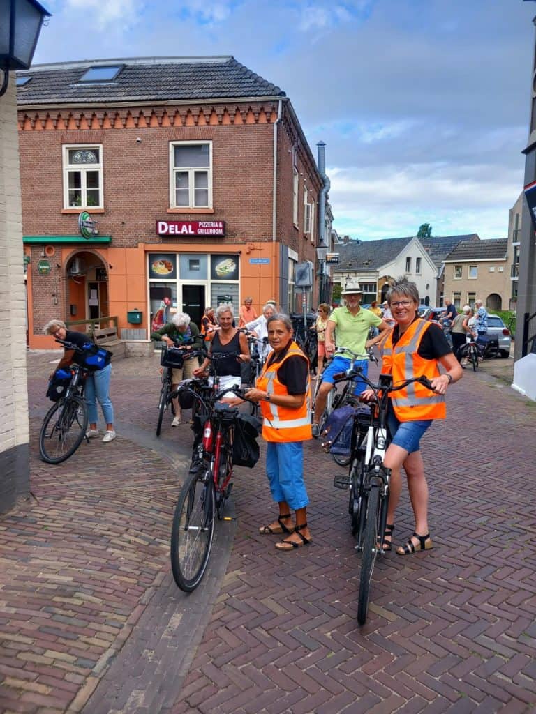 Fietsen op 't Gelders Eiland met groep in oranje veiligheidsvesten, gezellige sfeer, historische geb.