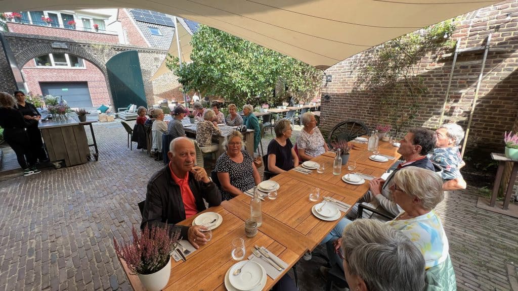 Gezellig terras met ouderen genieten van lunch op 't Gelders Eiland.