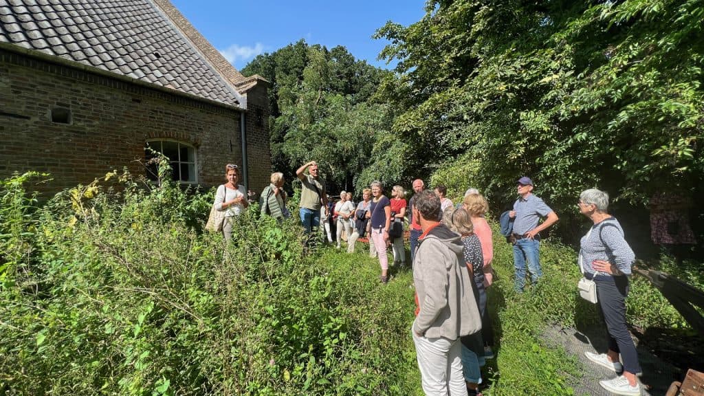 Gezelschap wandelt door groene omgeving op 't Gelders Eiland, genietend van natuur en cultuur.