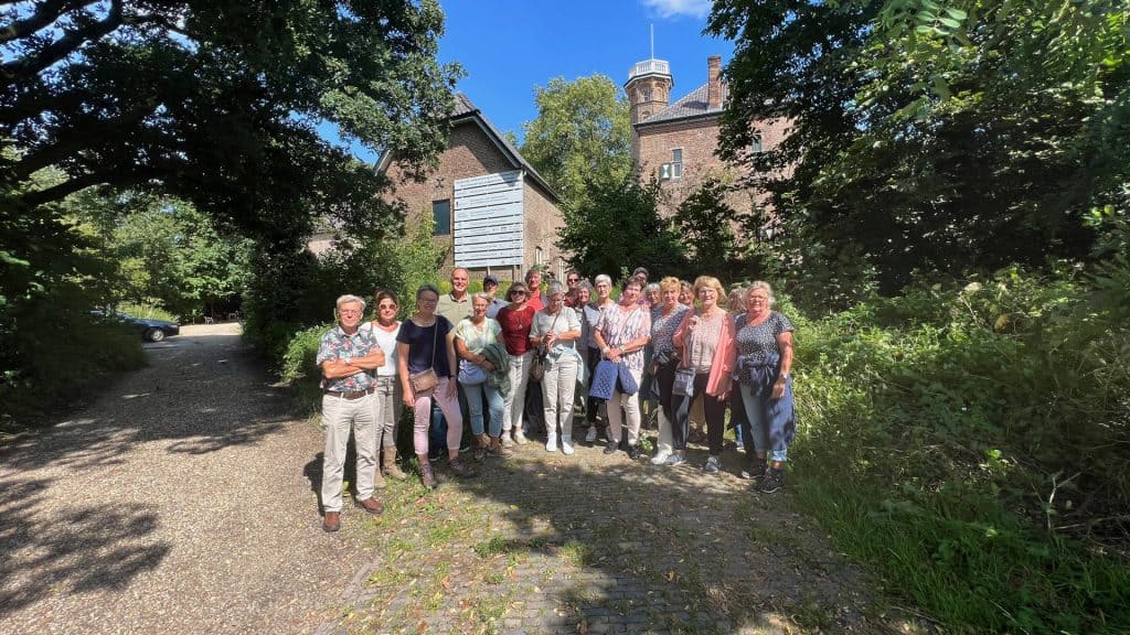 Gezelschap wandelaars op 't Gelders Eiland genieten van de natuur en historische gebouwen.