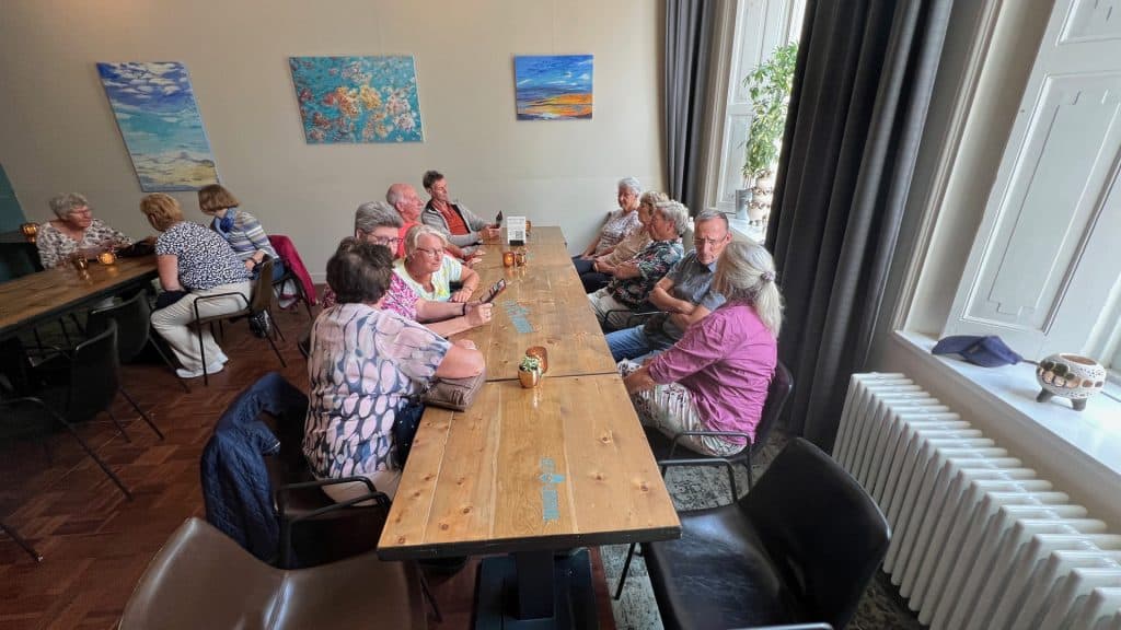 Gezellige groep ouderen aan tafel in een sfeervolle kamer op 't Gelders Eiland.