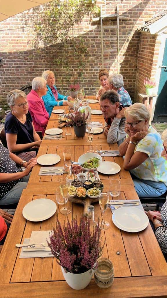 Gezellig gezelschap genieten van een maaltijd op 't Gelders Eiland in een sfeervolle tuin.