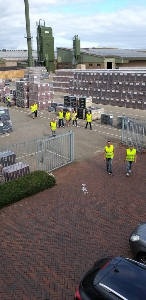Arbeiders in gele veiligheidsvesten bij opslag van bouwmaterialen op 't Gelders Eiland.
