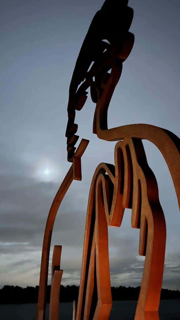 Houten kunstwerk met silhouet van een dier bij zonsondergang op 't Gelders Eiland.