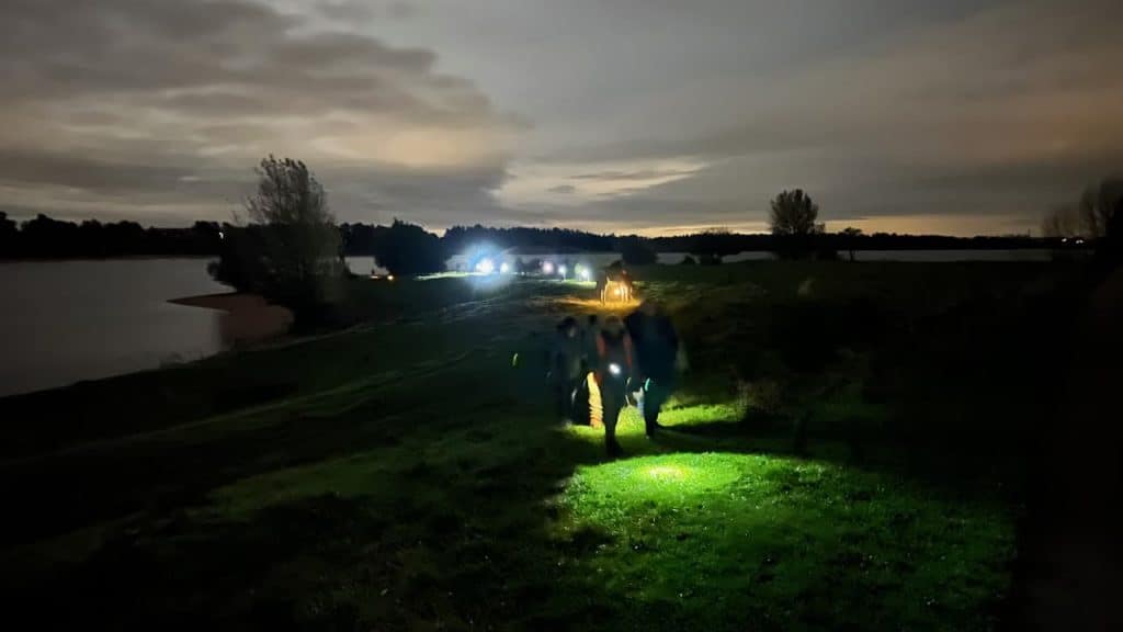 Zwemmen op 't Gelders Eiland bij zonsondergang met verlichte omgeving.