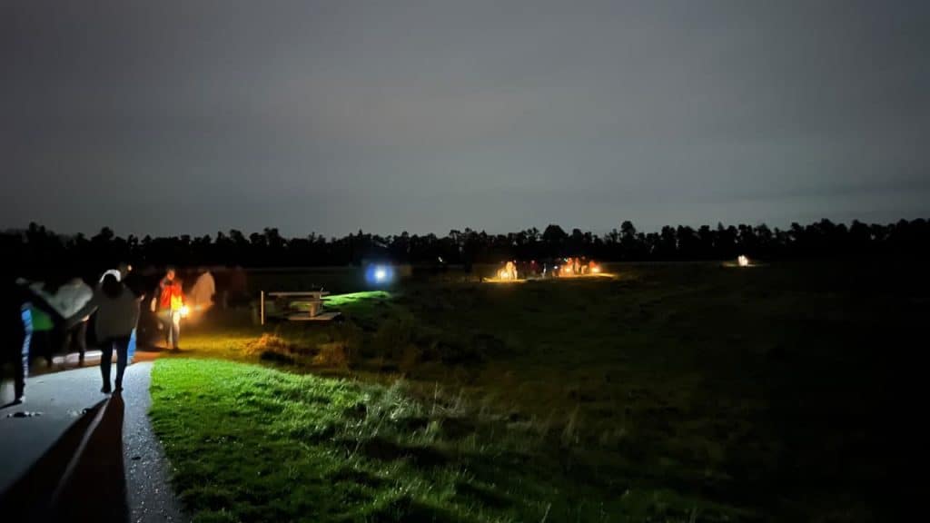 Sfeervolle avondfoto van 't Gelders Eiland met verlichte paden en mensen die genieten in de natuur.
