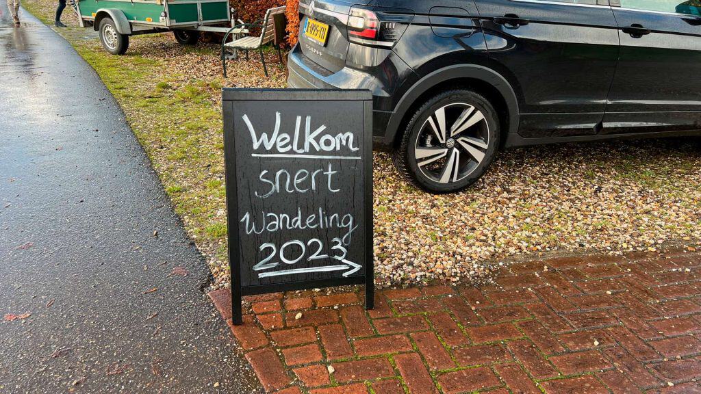 Welkomsbord voor wandelaars op 't Gelders Eiland, 2023, met parkeerplaats en auto op de achtergrond.