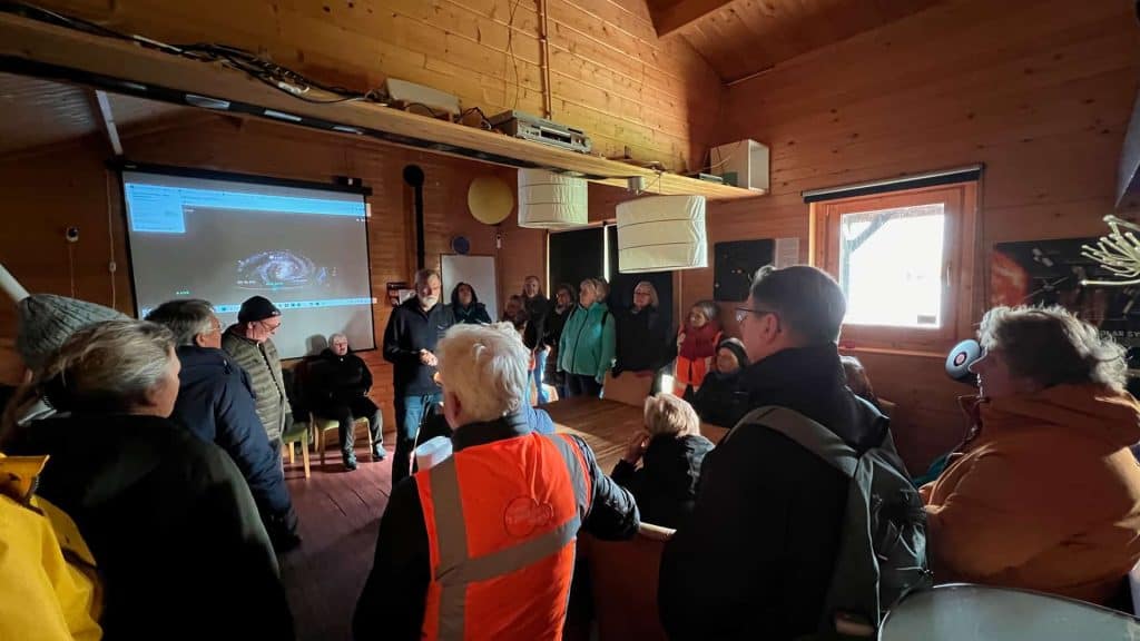 Gezellige bijeenkomst op 't Gelders Eiland met mensen die luisteren naar een presentatie in een hout.