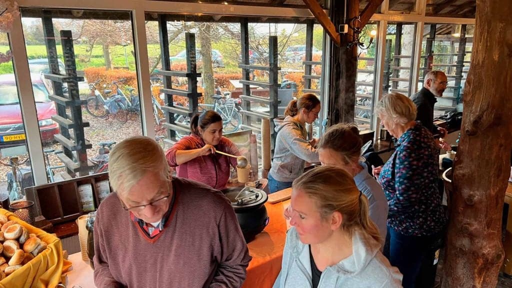 Gezellige binnenruimte met mensen die genieten van een maaltijd op 't Gelders Eiland. Rustige sfeer.