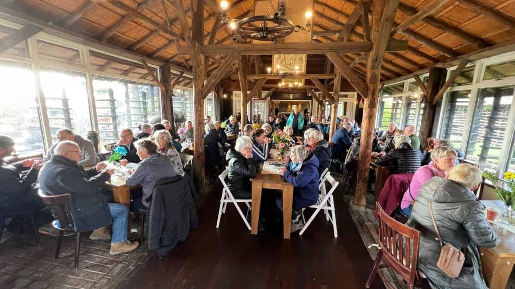 Gezellige groep mensen dineert in een rustieke houten restaurant op 't Gelders Eiland.