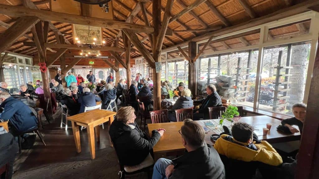 Gezellige binnenruimte op 't Gelders Eiland met mensen die genieten van een maaltijd.