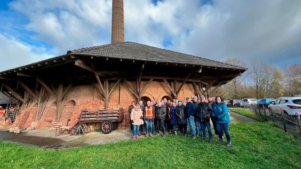 Kleine groep mensen bij historisch gebouw op 't Gelders Eiland, met een grote schoorsteen op de acht.
