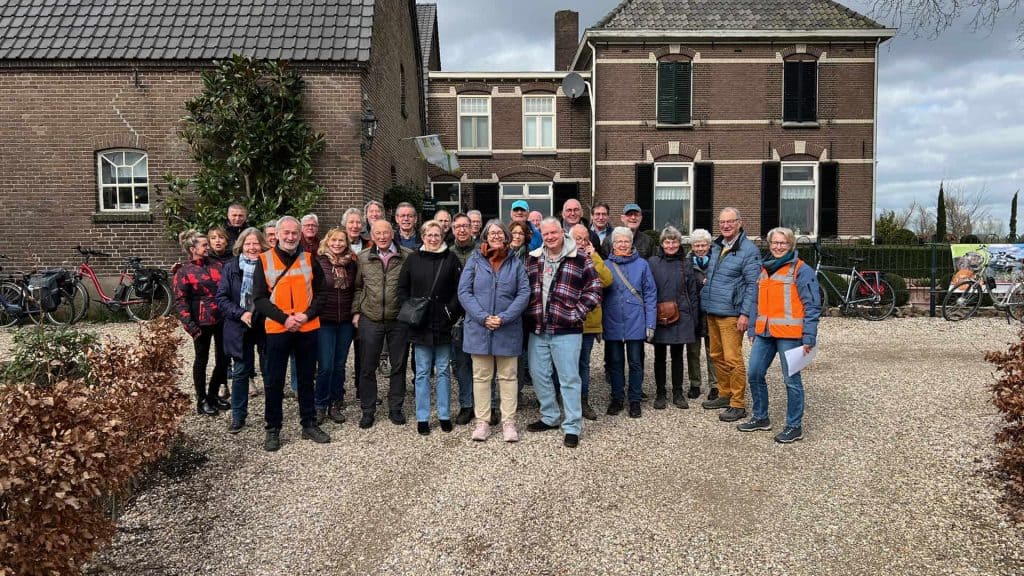 Heren en dames in een groep voor historische gebouwen op 't Gelders Eiland, met fietsen op de achter.