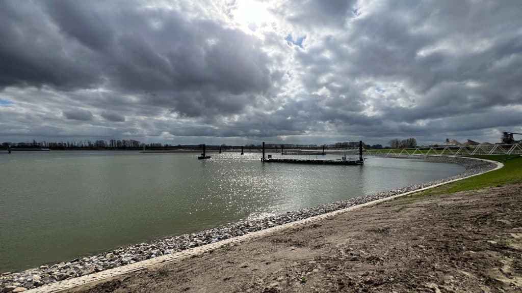 Zicht op de rivier en de haven van 't Gelders Eiland onder een bewolkte hemel.