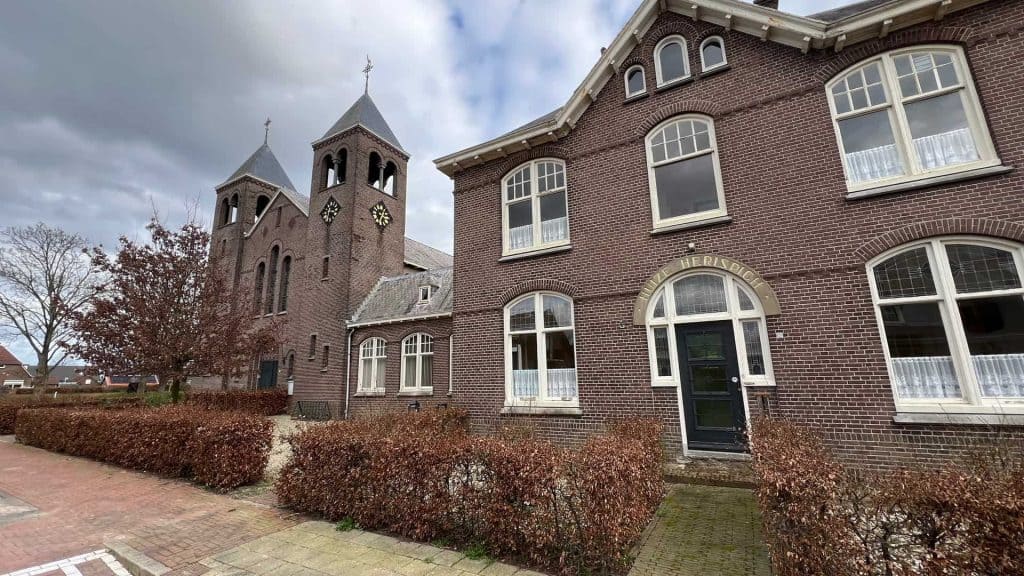 Kerk en historische gebouwen op 't Gelders Eiland in Arnhem, met kleurrijke herfstbomen en een gezel.