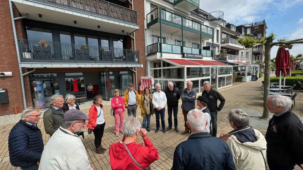 Gezellig groepje toeristen bij haven op 't Gelders Eiland, genietend van de rivier en stadsuitzicht.