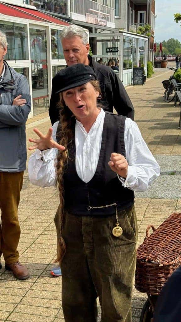 Hollandse vrouw in traditionele klederdracht op 't Gelders Eiland, levendige sfeer en lokale cultuur.