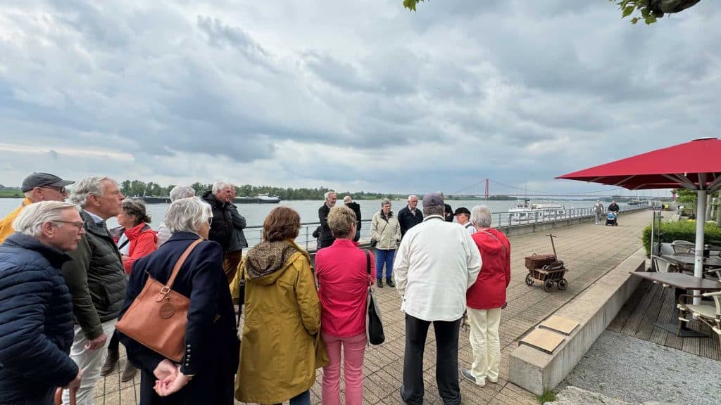 Gezellige groep toeristen bij haven op 't Gelders Eiland onder bewolkte hemel.