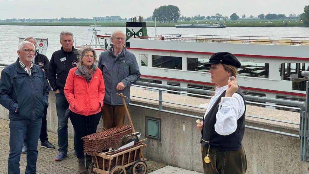 Groepsreis op 't Gelders Eiland met gids en boot in de achtergrond.