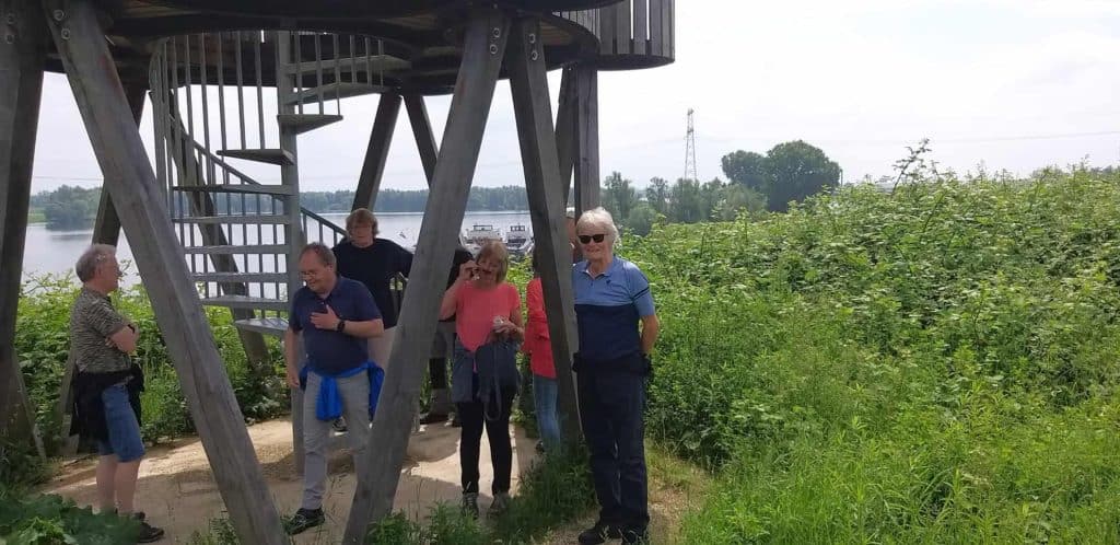 Zicht op uitkijktoren op 't Gelders Eiland met bezoekers en groene omgeving.